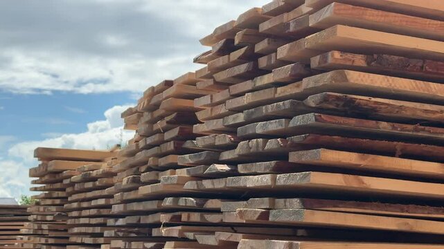 vertical video of a tall stack of pine planks, lumber in an open-air warehouse, natural materials for wood construction