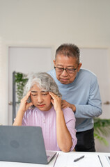 Senior couple checking bills and calculating expenses using a calculator at home, debt taxes and...