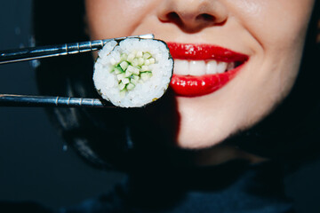 Smiling woman holding sushi with chopsticks, showcasing vibrant flavors and culinary delight in a...
