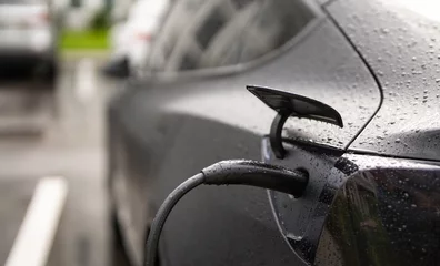 Fotobehang Electric battery car charge at EV station. concept of EV car and home charging station. Electric car charging. Electric car with a connected charging cable. Charging point. © Volodymyr