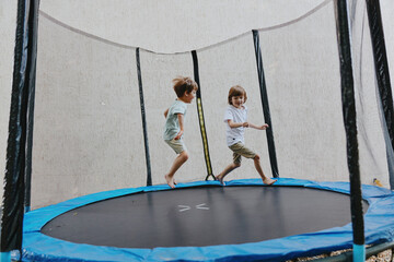 Active children playing on a trampoline, enjoying their time while jumping and laughing in a fun...