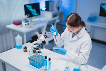 Female scientist working in a laboratory, using a pipette and petri dish, focused on research amid...