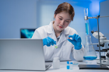 Dedicated female scientist in a laboratory setting, carefully handling samples and using a laptop....