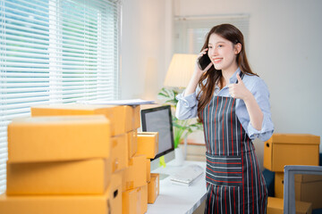 Young entrepreneur in home office managing online orders, talking on phone. Surrounded by parcels...