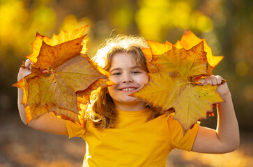 Autumnal kids mood. Little child in autumn orange leaves, outdoor portrait. Funny kids face with...