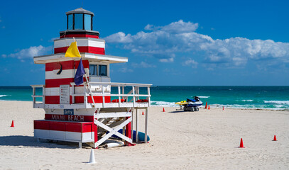Fototapeta premium Miami Beach lifeguard at the summer beach. Tourism on South Miami Beach. Sky above lifeguard tower in Miami. Iconic lifeguard tower on sand in Miami. A symbol of Miamis coast.