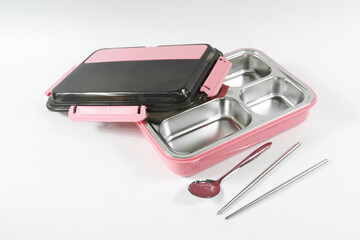 Plastic and stainless lunch box, which is black and pink in color. n white background, food...