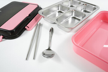 Plastic and stainless lunch box, which is black and pink in color. n white background, food...