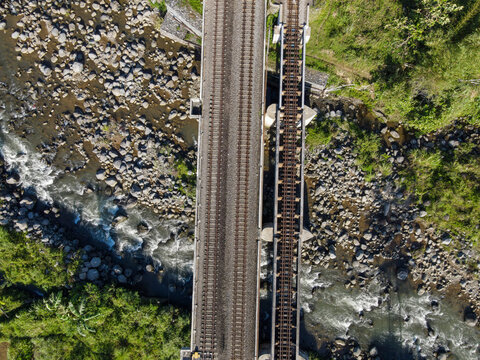 Aerial Photo of Railway Bridge Crossing River in Rural Area – Scenic Infrastructure for Transportation, Travel, Documentary, etc.
