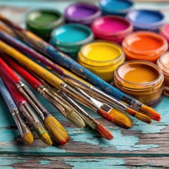Colorful paint containers and paintbrushes on a weathered surface