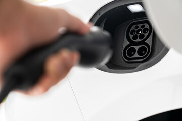 Hand holding EV charger near electric car socket