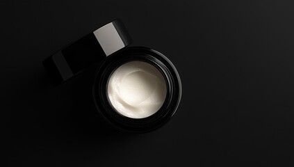 Opened black jar of cream on black background.