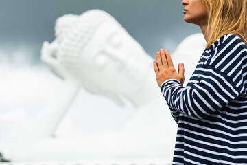 
A young girl of European appearance folds her hands in namaste and meditates in front of a huge...