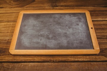 Blank rectangular chalkboard with wooden frame is lying flat on rustic wood table in flat design