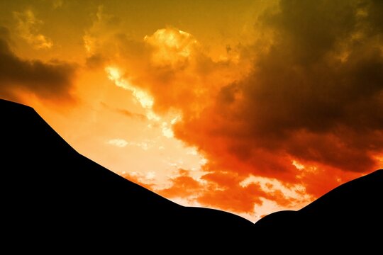 Fototapeta Flat illustration is showing silhouette of rolling hills against vibrant orange and red clouds