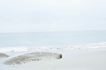 Flat rocky outcrop is appearing in minimalist flat design coastal scene, with tidal pool and waves