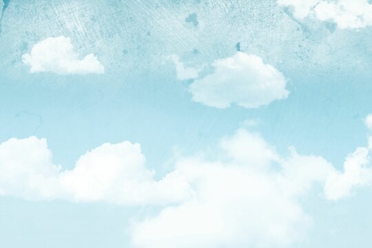Fototapeta White fluffy cumulus clouds are drifting across pastel blue sky in painterly grunge style