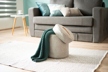 Felt storage ottoman with green knitted throw on geometric rug in a bright Scandinavian minimalist...