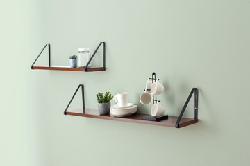 Wall-mounted dark wood floating shelves with black metal brackets, showcasing ceramic tableware,...