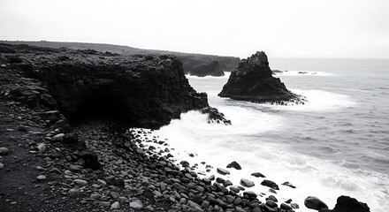 Dramatic black and white coastal scene featuring rugged cliffs, crashing waves, and a rocky shoreline under a misty sky.