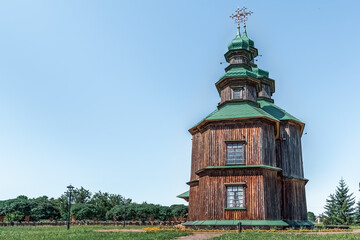 Wooden Orthodox church with green copper domes and ornate crosses in Pustoviitivka village, Sumy region. Fine example of Ukrainian timber religious architecture. Pustoviitivka, Ukraine - June 29, 2024