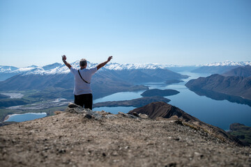 Rear view of hiking tourist  making a heart symbol at the top of Roys Peak Wanaka New Zealand