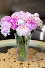 Beautiful peonies in glass vase on table.