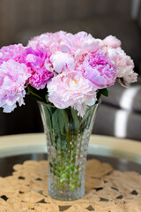 Beautiful peonies in glass vase on table.