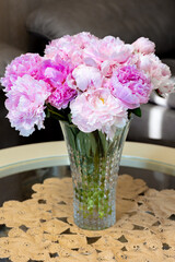 Beautiful peonies in glass vase on table.