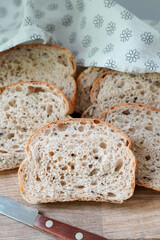 Sliced organic multigrain sourdough bread on a wooden board with bread knife
