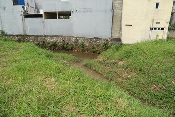 The garden is in a large area with a stretch of grass and a small river flowing amidst the hot sun and long grass