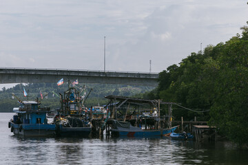 A traditional fishing boat is moored near a wooden house by the mangrove forest in Kuala Penyu,...