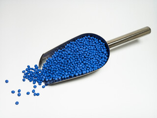 Blue plastic masterbatch, polymer carries colorful pigments with small scoops poured into a white background, suitable for product catalog design of industrial plastic manufacturing company profiles