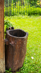 Fototapeta premium A rustic, hollowed-out tree stump, possibly a planter, sits on vibrant green grass beside a wooden post