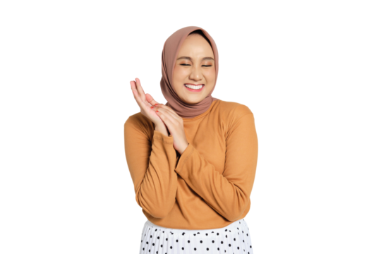 Joyful young Muslim woman in hijab smiling with closed eyes and clasped hands isolated on transparent background