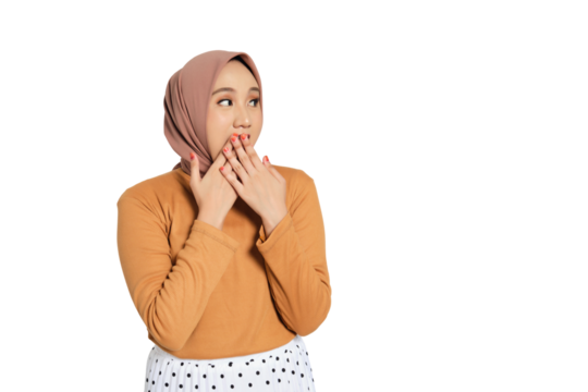 Surprised young Muslim woman in hijab covering mouth with both hands and looking away isolated on transparent background