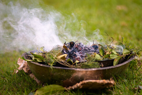 An Indigenous smoking ceremony showing native leaves on fire and smoking - horizontal