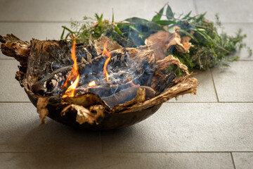 An Indigenous smoking ceremony showing native leaves on fire and smoking