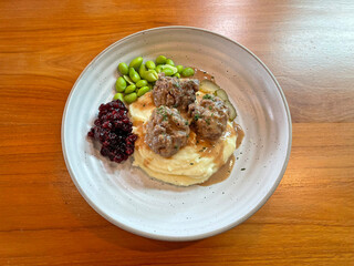 Meatball served with berry jam, vegetables and mashed potato