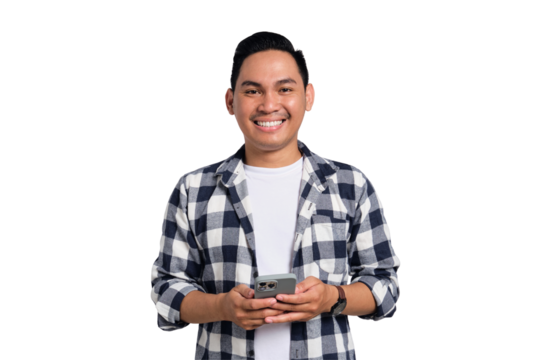 Smiling young man in checkered shirt using smartphone while standing and looking at camera isolated on transparent background
