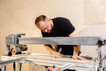 Construction worker using tile saw cutting machine preparing ceramic tiles for bathroom renovation