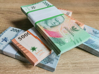 Bundles of Indonesian Rupiah Banknotes displayed on a wooden surface.
A business and finance conceptual.