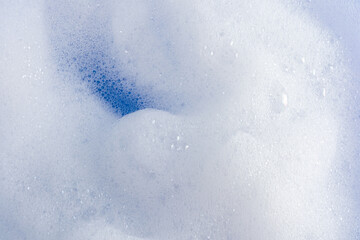 Beautiful whipped soap product foam. gaps of blue water. Abstract texture background of dense white foam. A copy of the space.