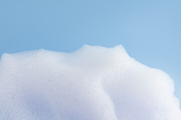 Texture of white bubble bath, soap, laundry detergent on a blue background. Layout for the presentation of your cosmetic product.