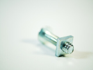 Close up of a shiny metal bolt with a square head isolated against a plain white background for industrial applications.