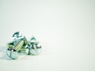 Close up of screws with a slotted drive over a white surface shows hardware and fasteners, tools