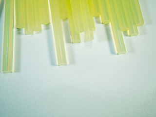 Transparent hot melt glue sticks arranged on a white surface creates a crafting or construction...