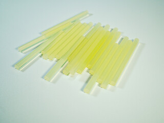 Hot melt glue sticks lying on a clean white surface, used in crafting and DIY projects for bonding materials together.