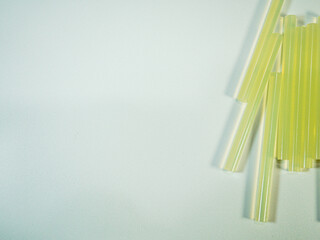 Craft supplies featuring light yellow glue sticks resting on a textured, sparkling surface for art...