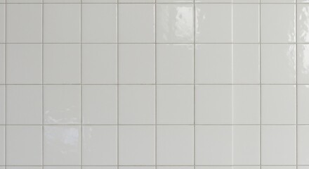White square tiles arranged in a uniform grid pattern on a wall with subtle surface reflections and light gray grout